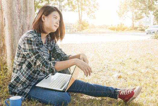 young woman sitting with laptop at park