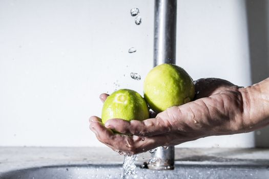 Two lemon on male hand cleaning with falling water