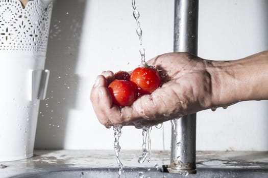 Tomatoes on male hand with falling water,Cleaning food
