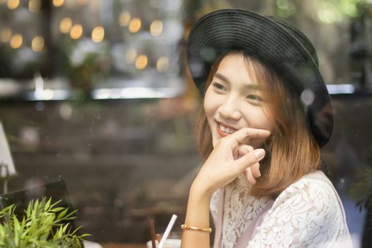 A shot of a beautiful asian woman  in a cafe (shot through window)