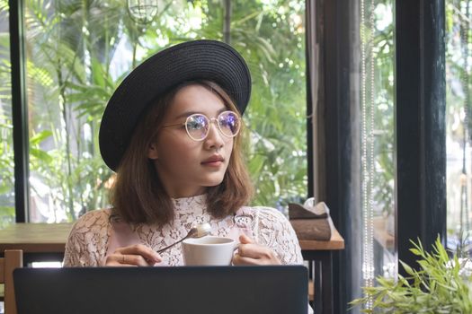 Asian women with coffee and working on laptop in the cafe