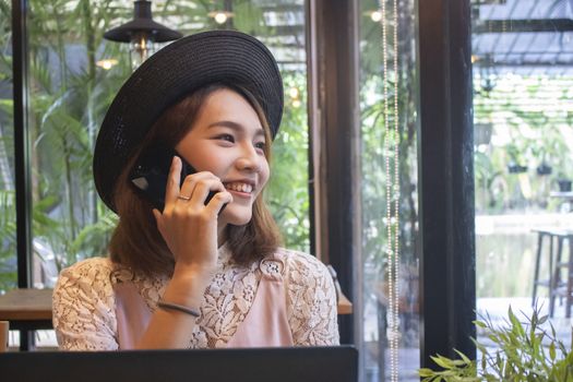 Smiling asian girl talking phone in cafe