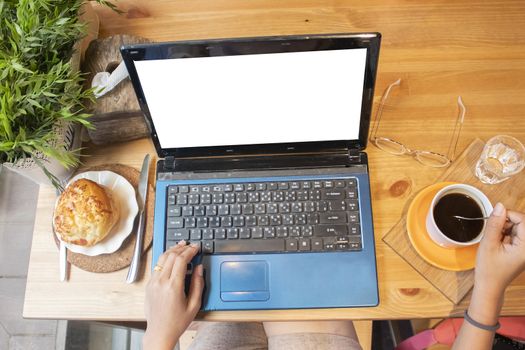 Women hand on laptop with coffee cup on table in cafe,Top view