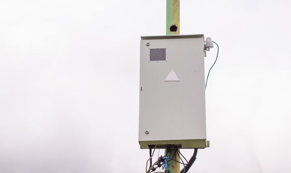 White electric box on a pole outside the house. Industrial, urban electric box