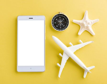 World Tourism Day, Top view of minimal model plane, airplane, starfish, alarm clock, compass and smartphone blank screen, studio shot isolated on yellow background, accessory flight holiday concept