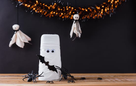 Funny Halloween day decor party concept, The mummy ghost on water glass wrapped around with bandage and have bats and spider stick it found only eyes, studio shot isolated on black background