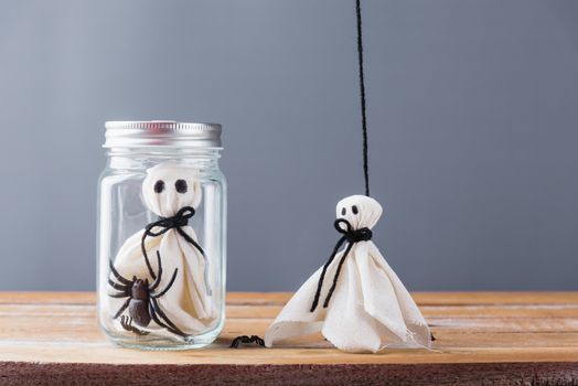 Funny Halloween day decoration party, closeup white ghost and spider in jar on wooden wall gray background and copy space, studio shot isolated, Happy holiday concept