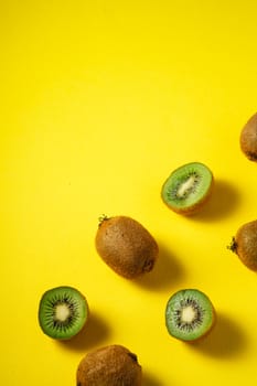 Kiwi fruits half sliced on yellow background, top view flat lay