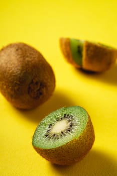 Kiwi fruits half sliced on yellow background, angle view