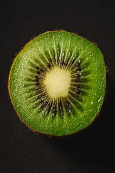 Kiwi fruit half sliced on dark background, macro