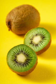 Kiwi fruits half sliced on yellow background, angle view