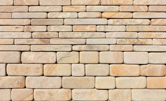 Wall background and texture of hewn rounded yellow sandstone stone, close-up.