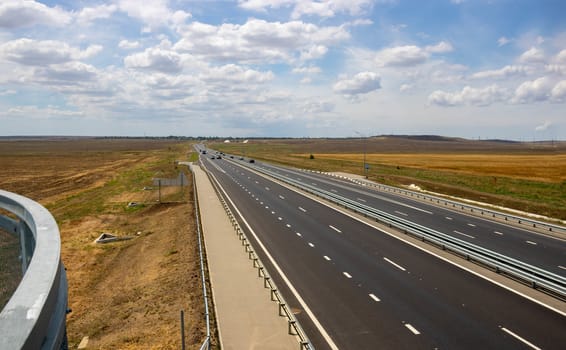 highway in the steppe against the blue sky, a long road stretching into the distance.