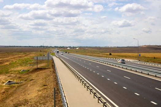 highway in the steppe against the blue sky, a long road stretching into the distance.