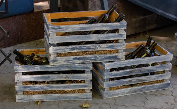 Empty wine bottles in gray wooden crates.