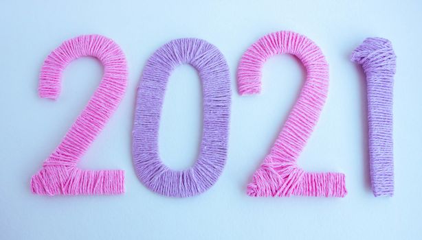 The numbers 2021 are made of pink and lilac threads on a white background. The concept of a New year.