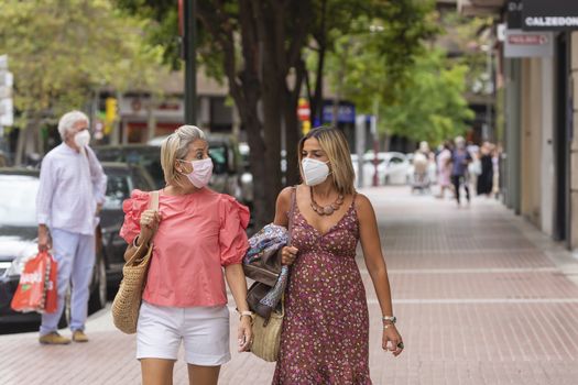 Zaragoza, Spain - August 18, 2020: Couple of women walking with face masks, due to the coronavirus pandemic, in the central area of Zaragoza.