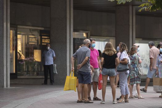 Zaragoza, Spain - August 18, 2020: Group of people talking with face masks, due to the coronavirus pandemic, in the central area of Zaragoza.