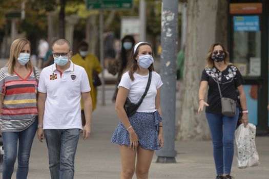 Zaragoza, Spain - August 18, 2020: Young girl waiting in a crosswalk with face mask, due to the coronavirus pandemic, in the central area of Zaragoza.