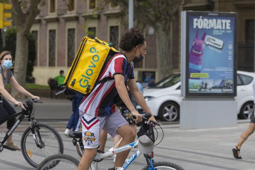 Zaragoza, Spain - August 18, 2020: Glovo rider working with face mask, due to the coronavirus pandemic, in the central area of Zaragoza.