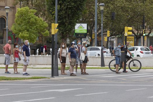 Zaragoza, Spain - August 18, 2020: People waiting in a crosswalk with face masks, due to the coronavirus pandemic, in the central area of Zaragoza.