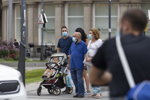 Zaragoza, Spain - August 18, 2020: People waiting in a crosswalk with face masks, due to the coronavirus pandemic, in the central area of Zaragoza.