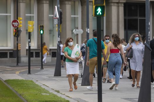 Zaragoza, Spain - August 18, 2020: People walking in a crosswalk with face masks, due to the coronavirus pandemic, in the central area of Zaragoza.