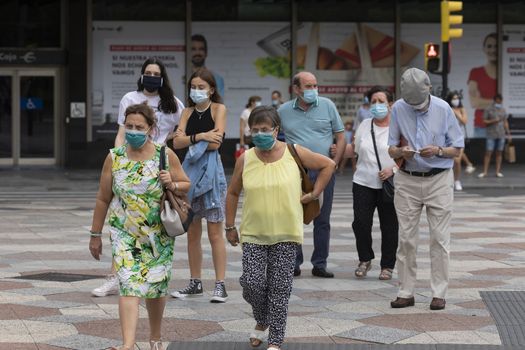 Zaragoza, Spain - August 18, 2020: People walking in a crosswalk with face masks, due to the coronavirus pandemic, in the central area of Zaragoza.