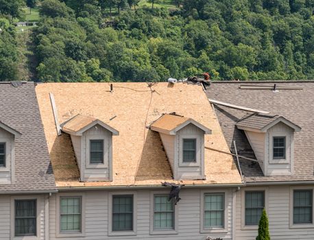 Roofing contractor has removed all the old tiles from townhouse roof before replacing with new shingles