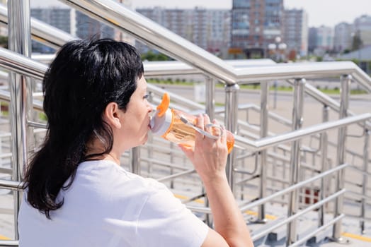 Sport and fitness. Senior sport. Active seniors. Smiling senior woman drinking water after workout outdoors on urban background