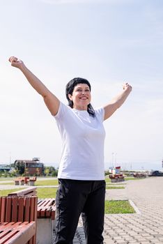 Sport and fitness. Senior sport. Active seniors. Smiling senior woman doing warm up before training outdoors in the park