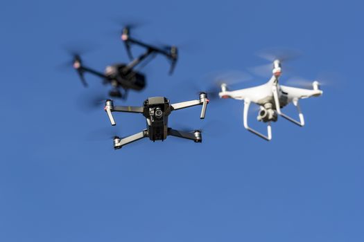 A group of drones fly through the air against a blue sky