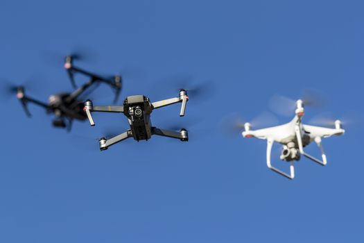 A group of drones fly through the air against a blue sky