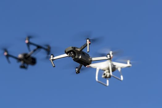 A group of drones fly through the air against a blue sky