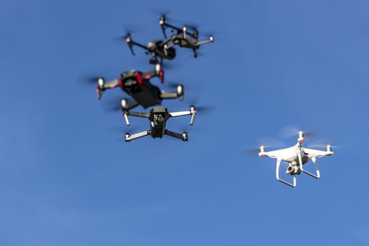 A group of drones fly through the air against a blue sky