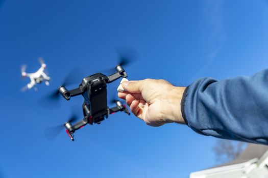 A group of drones fly through the air against a blue sky