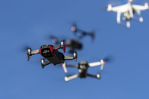 A group of drones fly through the air against a blue sky