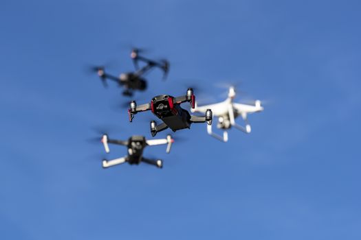 A group of drones fly through the air against a blue sky