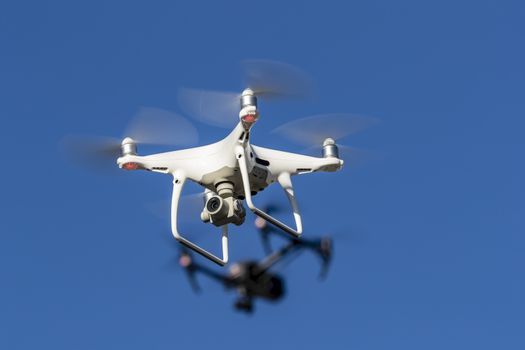 A group of drones fly through the air against a blue sky