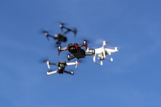 A group of drones fly through the air against a blue sky