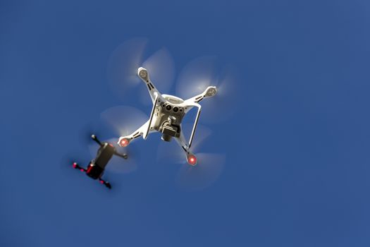 A group of drones fly through the air against a blue sky