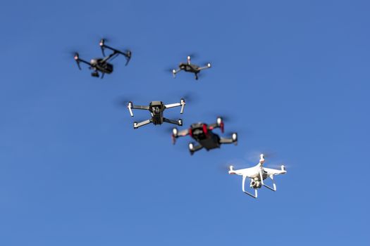 A group of drones fly through the air against a blue sky