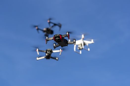 A group of drones fly through the air against a blue sky