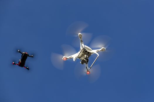 A group of drones fly through the air against a blue sky