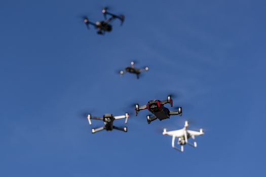 A group of drones fly through the air against a blue sky