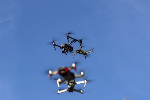 A group of drones fly through the air against a blue sky