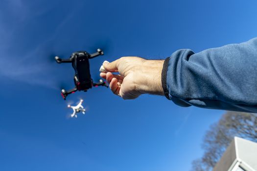 A group of drones fly through the air against a blue sky