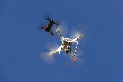 A group of drones fly through the air against a blue sky