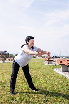 Sport and fitness. Senior sport. Active seniors. Smiling senior woman warming up stretching outdoors in the park