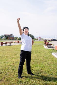 Sport and fitness. Senior sport. Active seniors. Happy senior woman in sports clothes exercising in the park standing with arms up